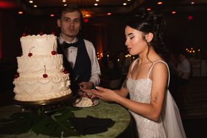 A couple shares their first bite of wedding cake at an elegant indoor reception.