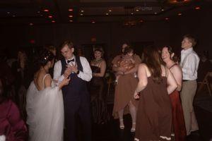 Dimly lit reception venue with guests dancing and socializing.
