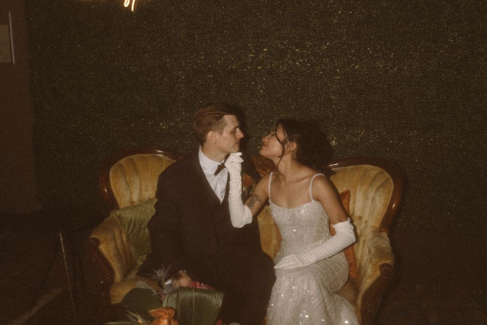A couple shares an intimate moment on a vintage yellow chair.