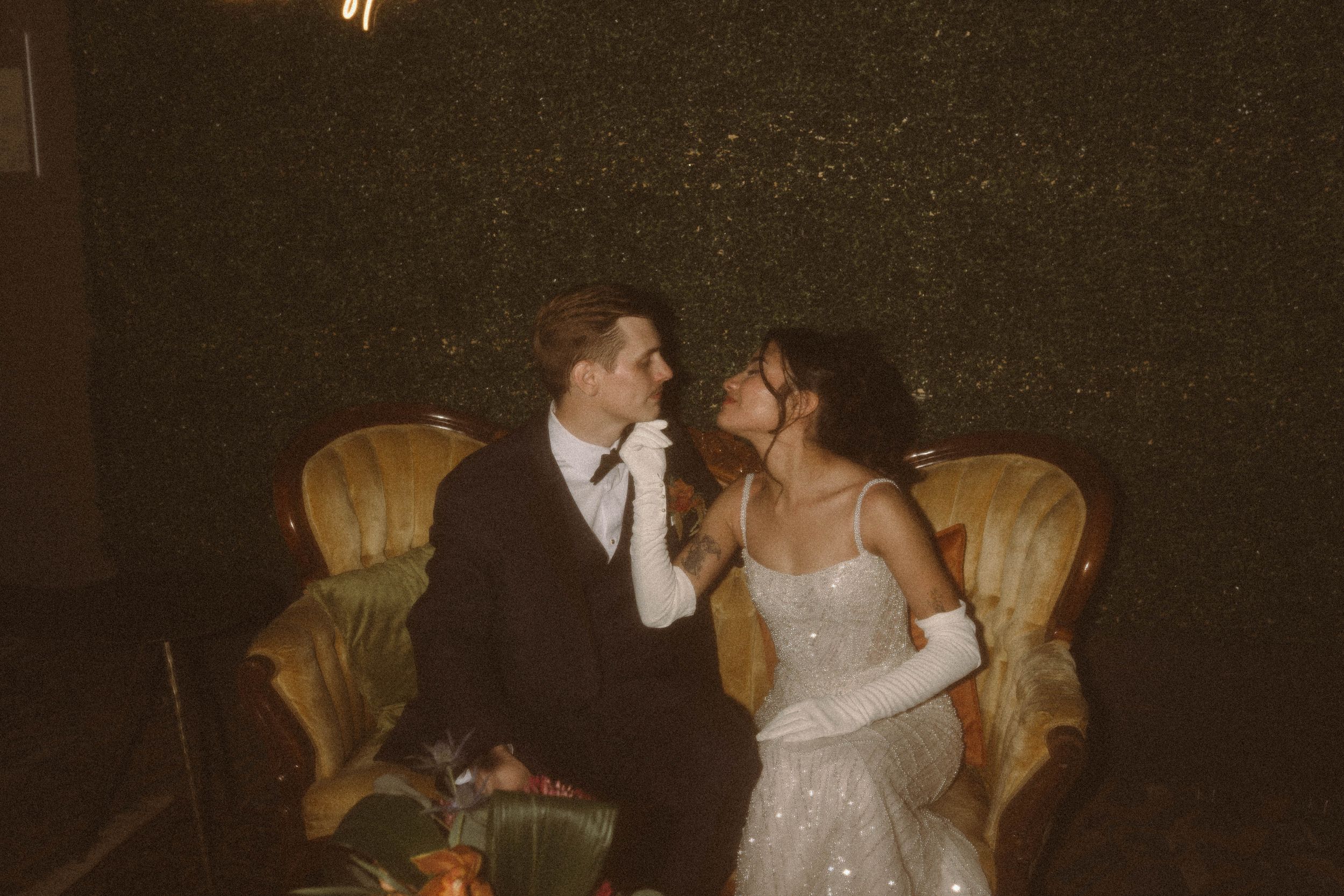 A couple shares an intimate moment on a vintage yellow chair.