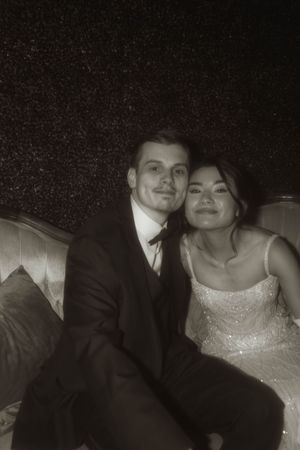 Couple in formal wedding attire share an intimate moment on an antique sofa.