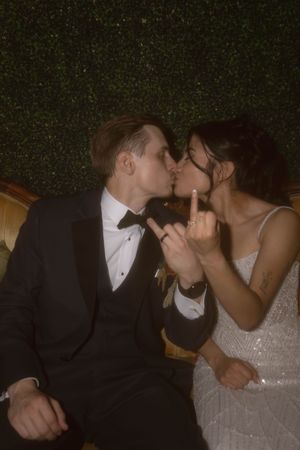 Romantic couple in wedding attire shares intimate moments on vintage seating.