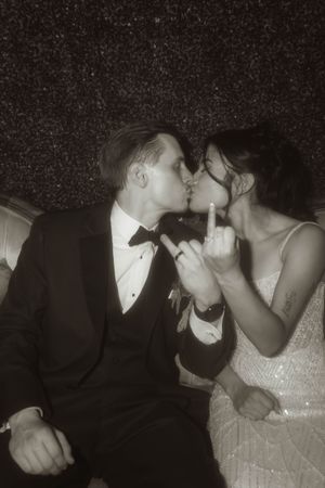 Couple in wedding attire shares tender moments on vintage furniture.
