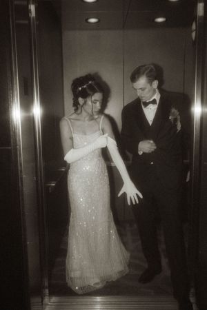 Couple in formal attire dances together in an elegant elevator setting.