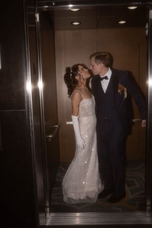 Couple in wedding attire sharing intimate moments in an elevator hallway.