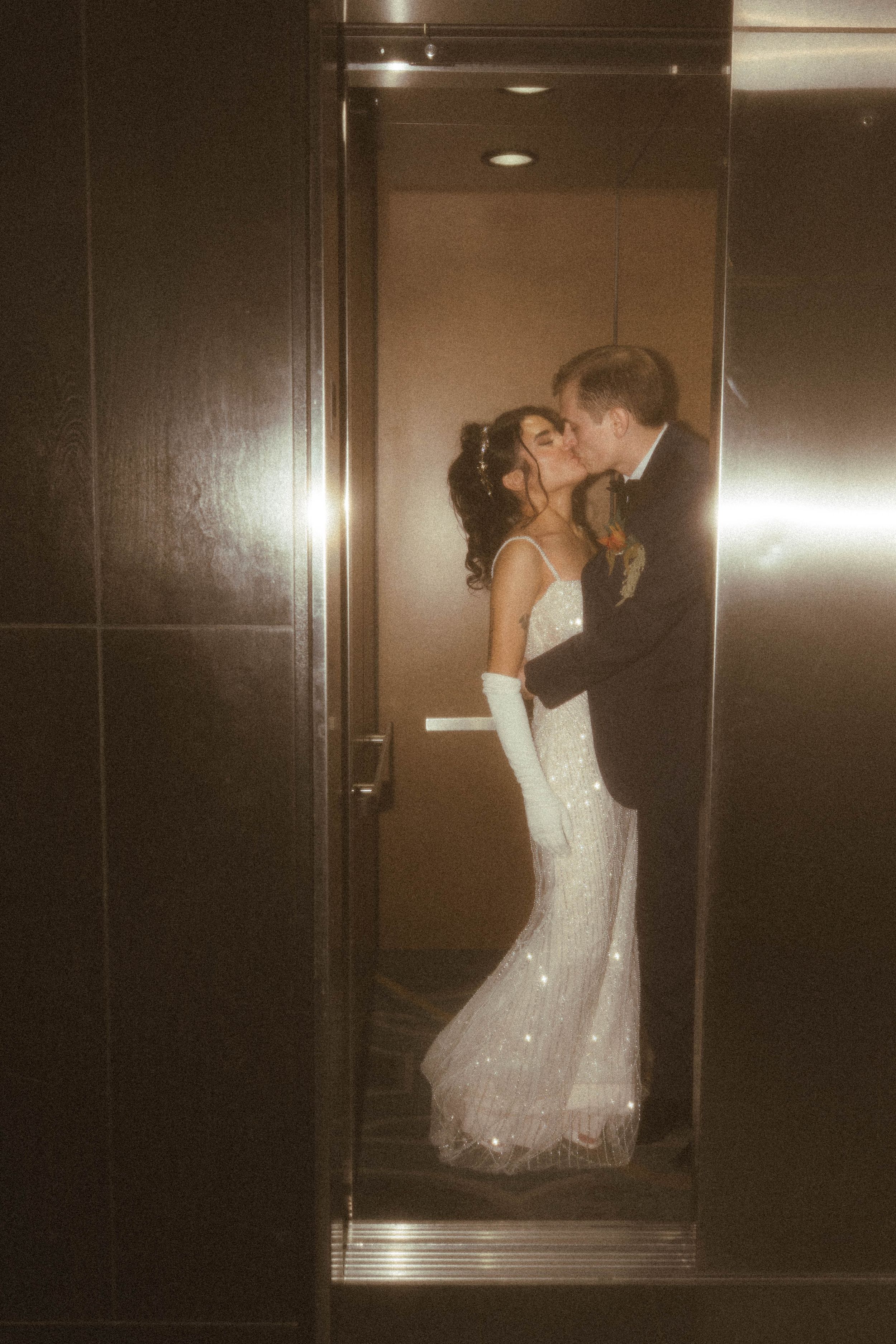 Romantic elevator photoshoot with sparkling dress details and dramatic lighting.
