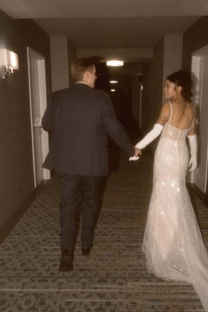 Couple walking down a hotel hallway with patterned carpet.