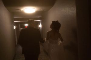 Dark hallway with overhead lighting and silhouettes of people walking.