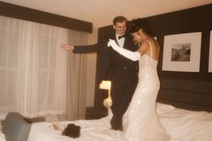 A couple shares a playful dance moment in their hotel room.