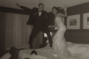 A couple in wedding attire dances together in a warmly lit room.