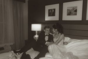 A sepia-toned intimate moment captured between newlyweds on a hotel bed.