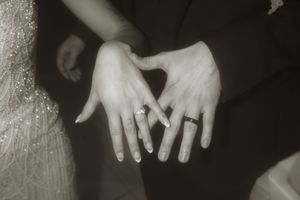 Close-up black and white photo of hands with wedding rings.