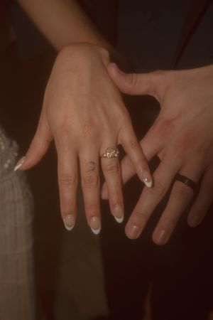 Close-up of wedding rings and manicured hands showing both engagement and wedding bands.