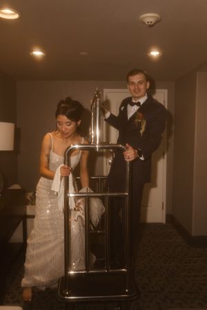 Wedding couple poses playfully near a modern metal railing in an indoor setting.