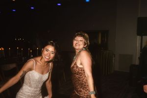 Two people dancing and having fun at a party wearing sparkly dresses.