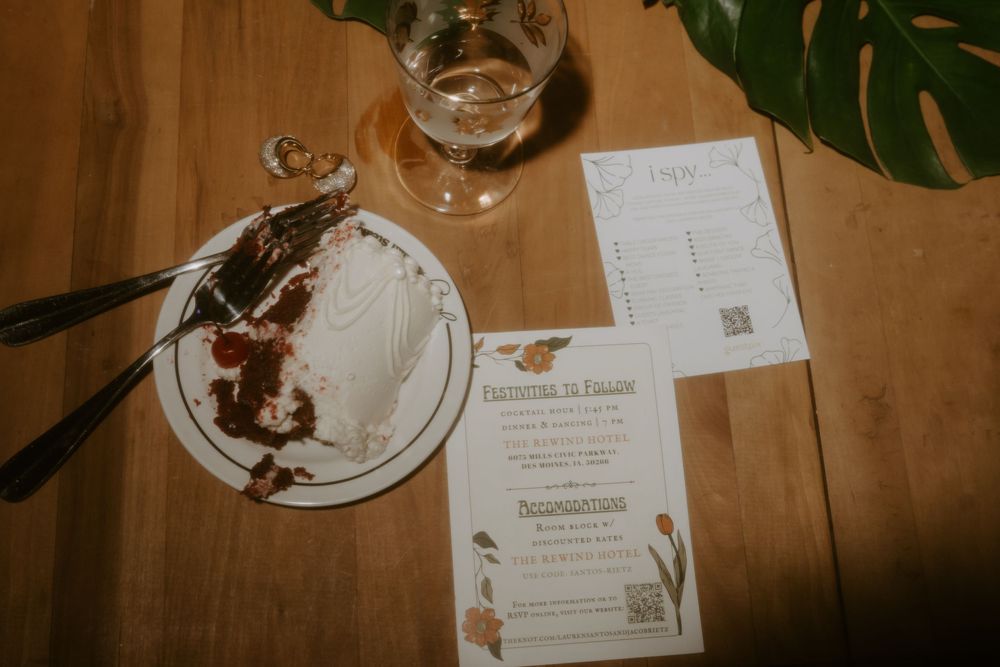 Wedding invitation with floral design next to an empty plate with chocolate remnants.