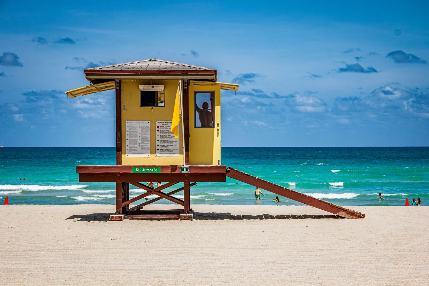 Yellow lifeguard station on Miami Beach with turquoise ocean waves and blue sky backdrop.