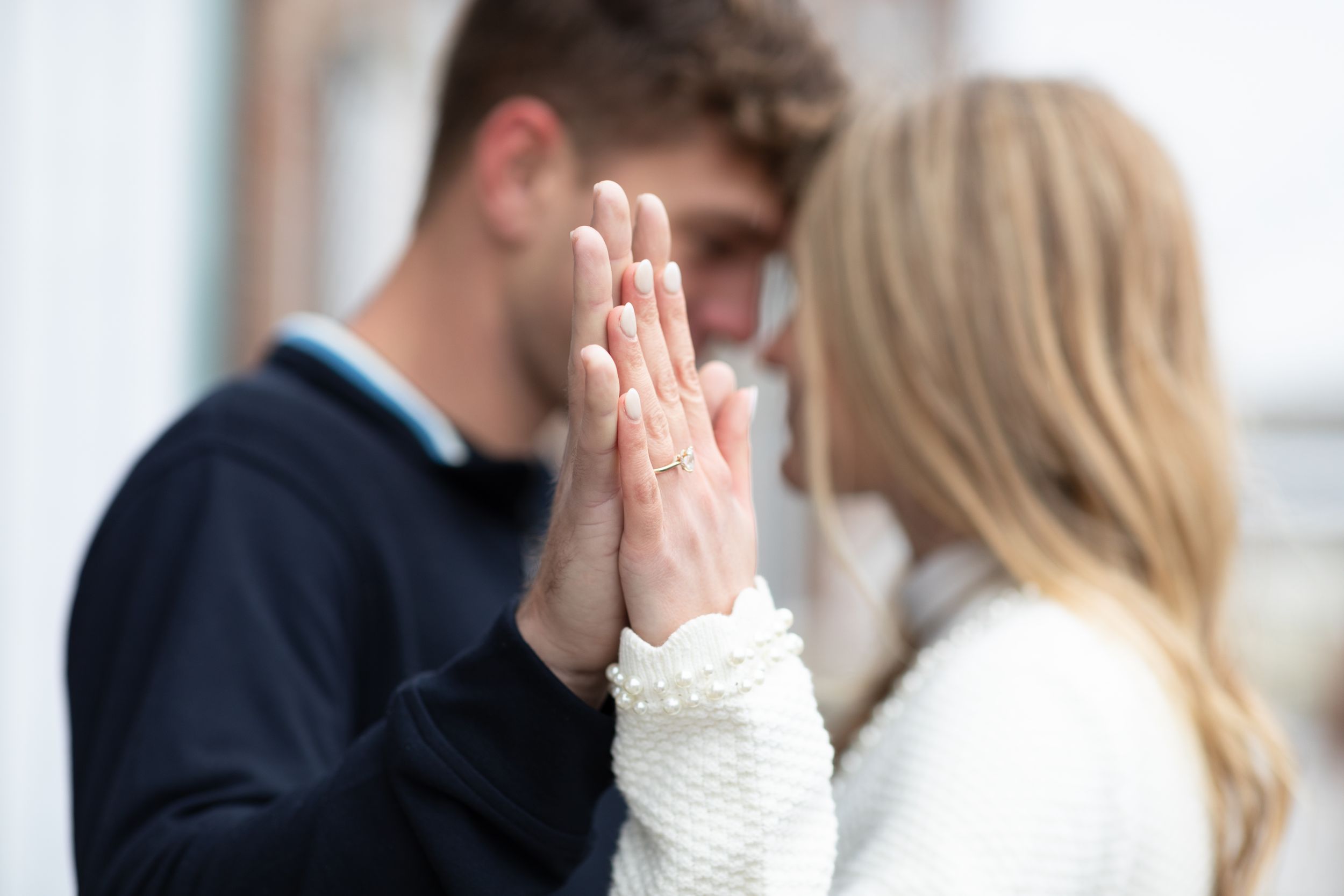A couple in matching navy and white outfits share an intimate moment against a brick wall background.