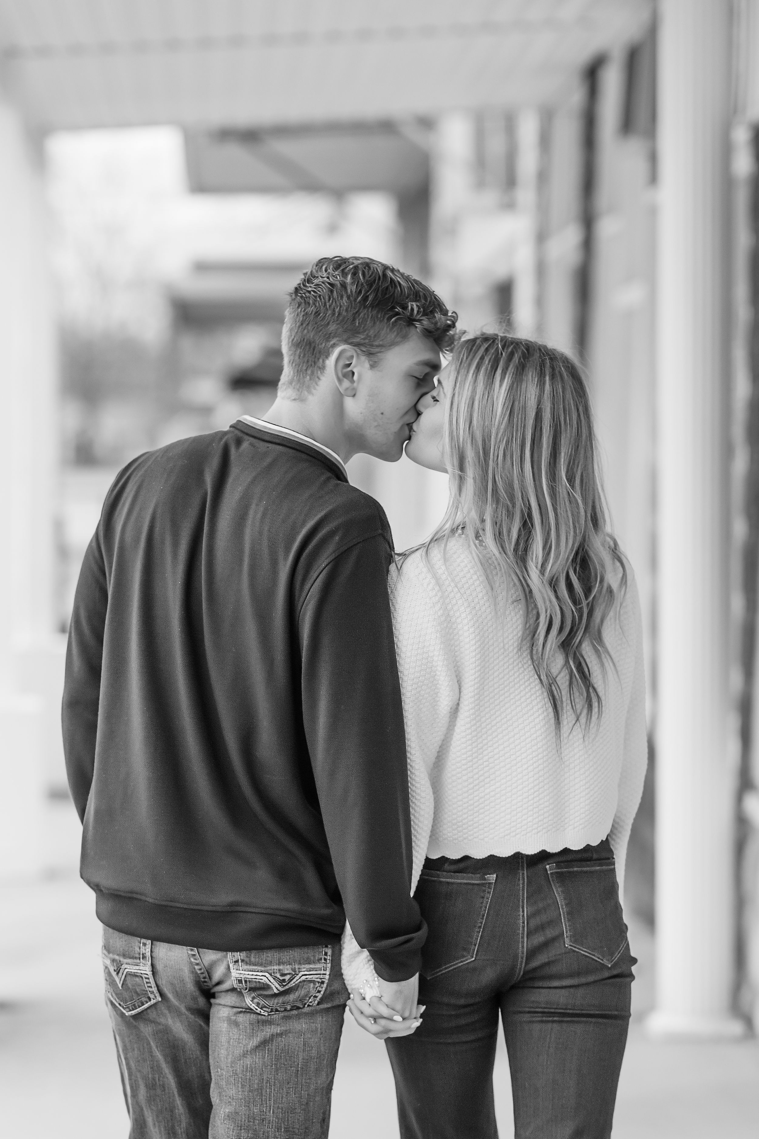 Black and white photo of couple holding hands while walking together.