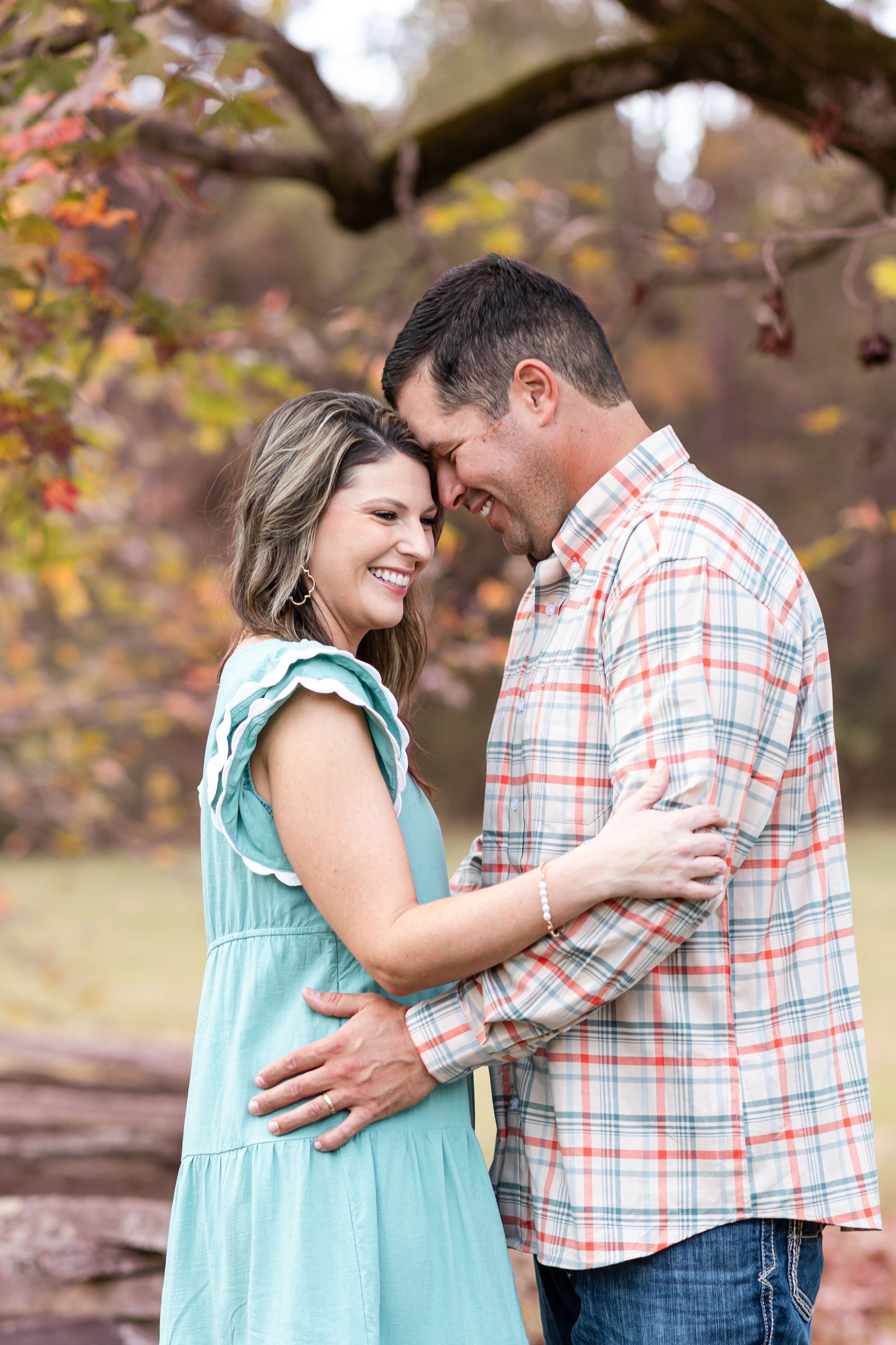 Couple sharing intimate moments in autumn setting with mint dress and plaid shirt.