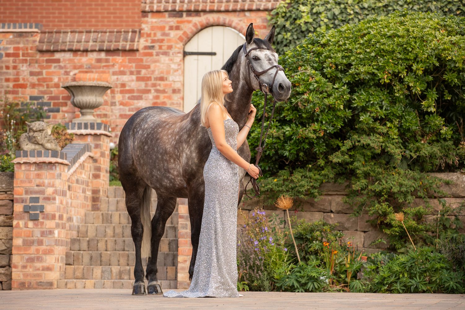 A horse and its rider enjoy an outdoor photoshoot session near rustic wooden fencing on a sunny day.