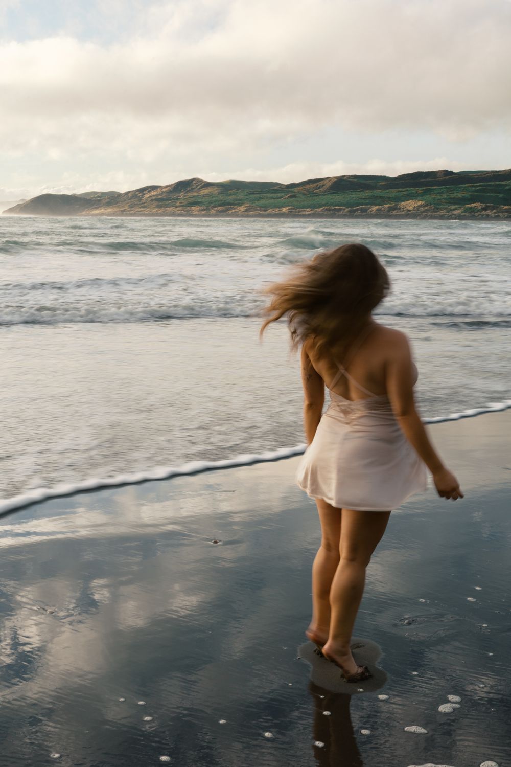 A sequence of photos showing someone in a white dress running and playing along a misty beach shoreline at sunset.