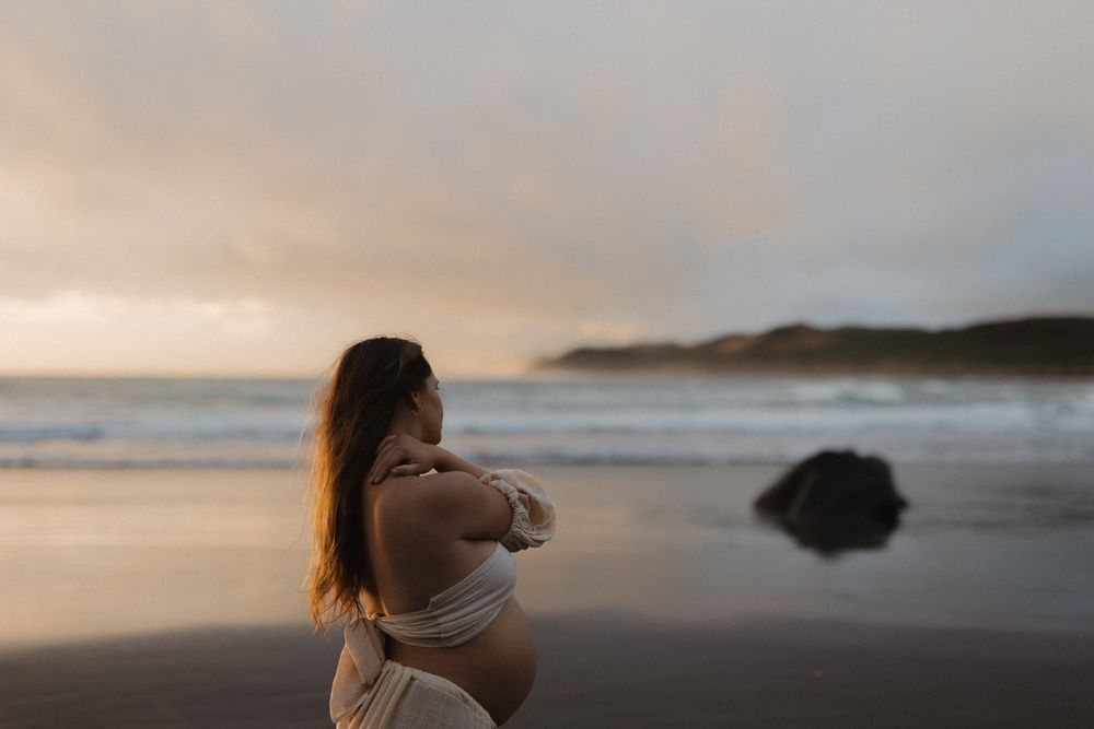 Atmospheric beach photography with warm sunset tones and coastal cliffs in the distance.