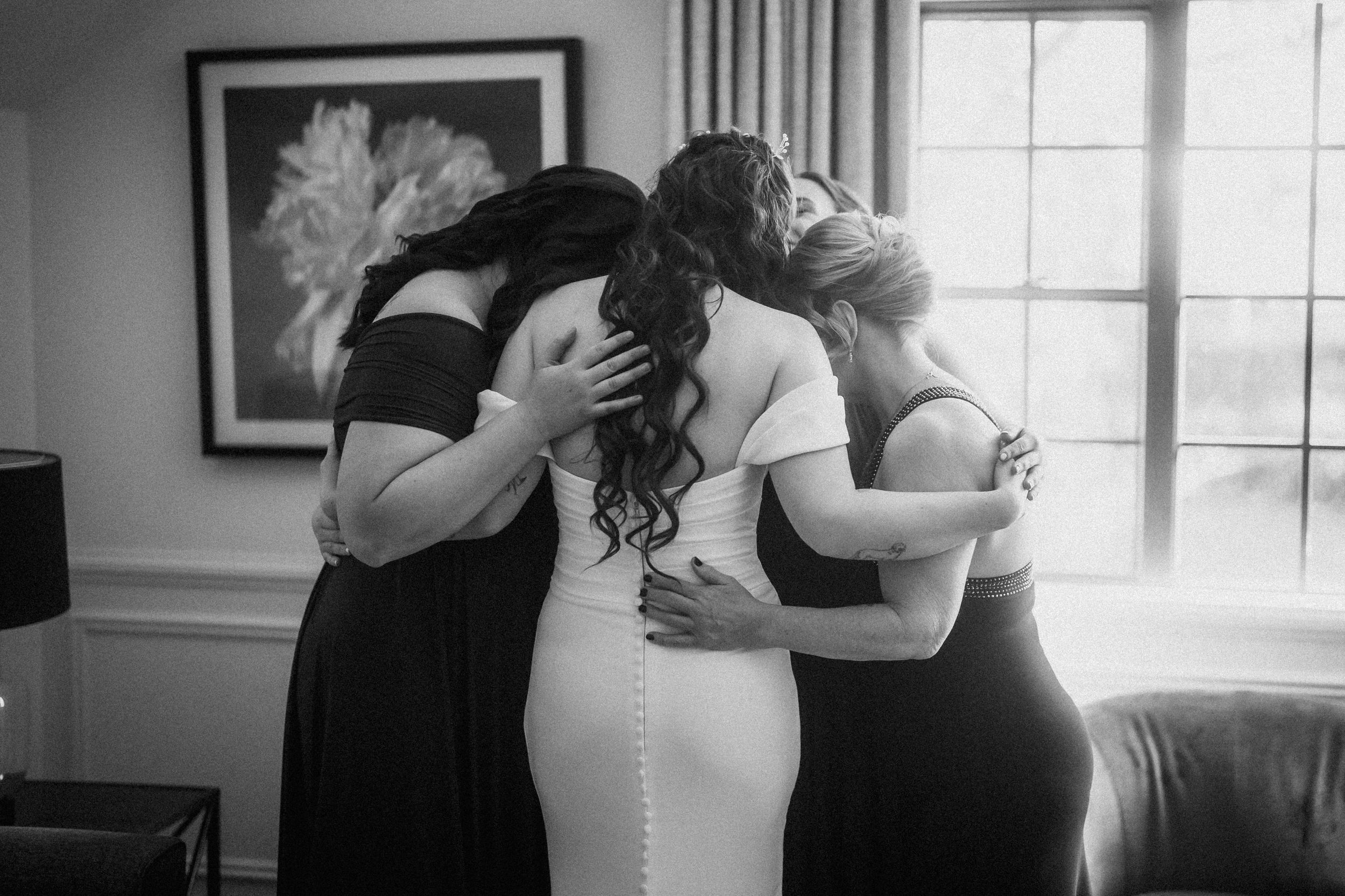 Black and white intimate wedding moment captured indoors with natural window light.