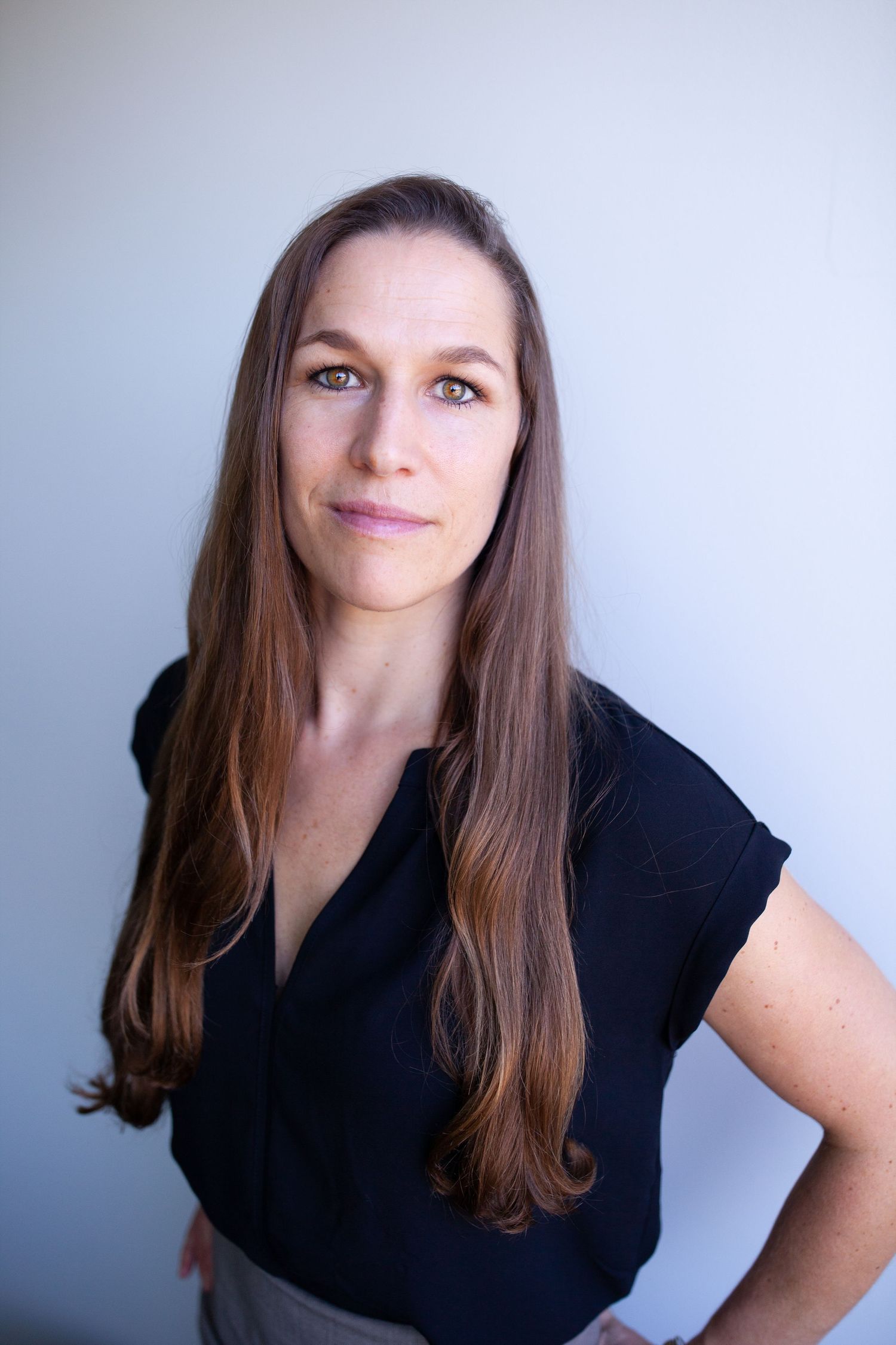 Professional headshot in black top against light gray background.
