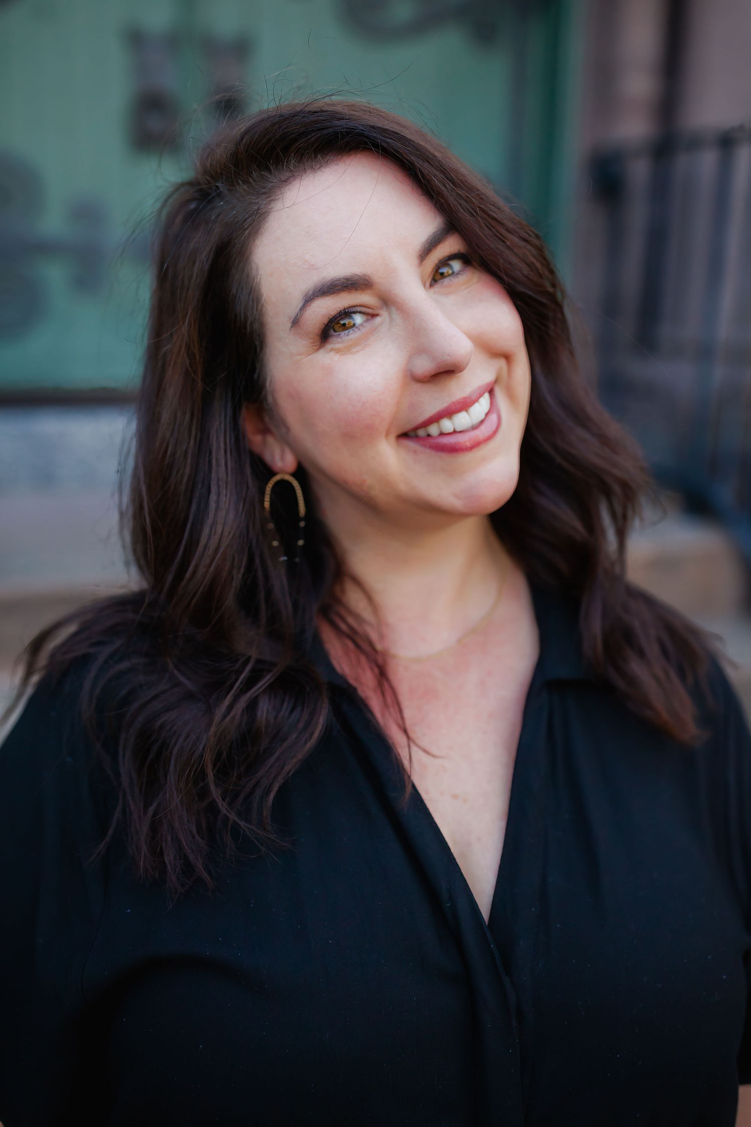 Professional headshot against a dark background showing a warm smile and dark hair.