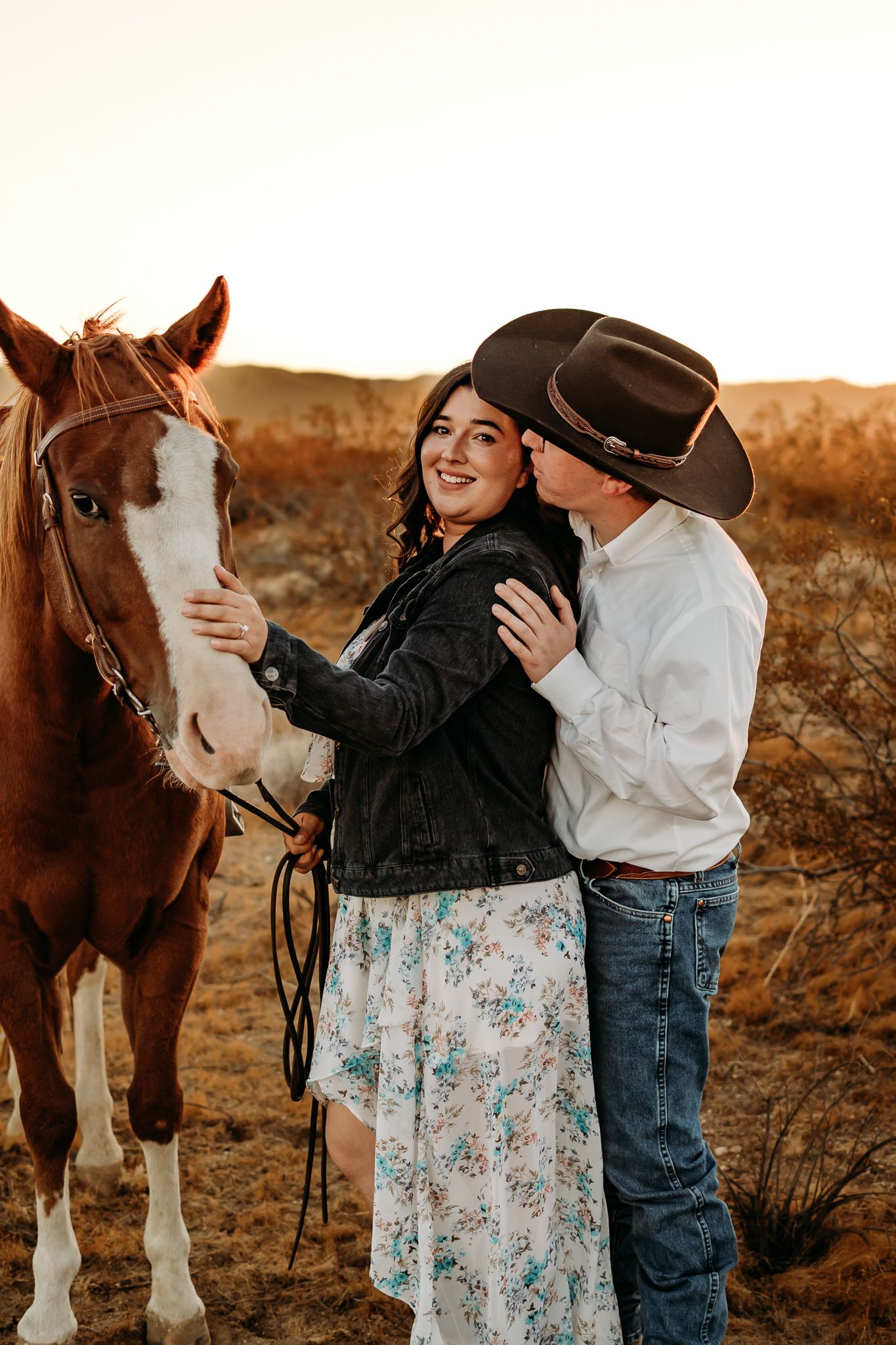 A couple shares a tender moment with their horse during a countryside photoshoot.