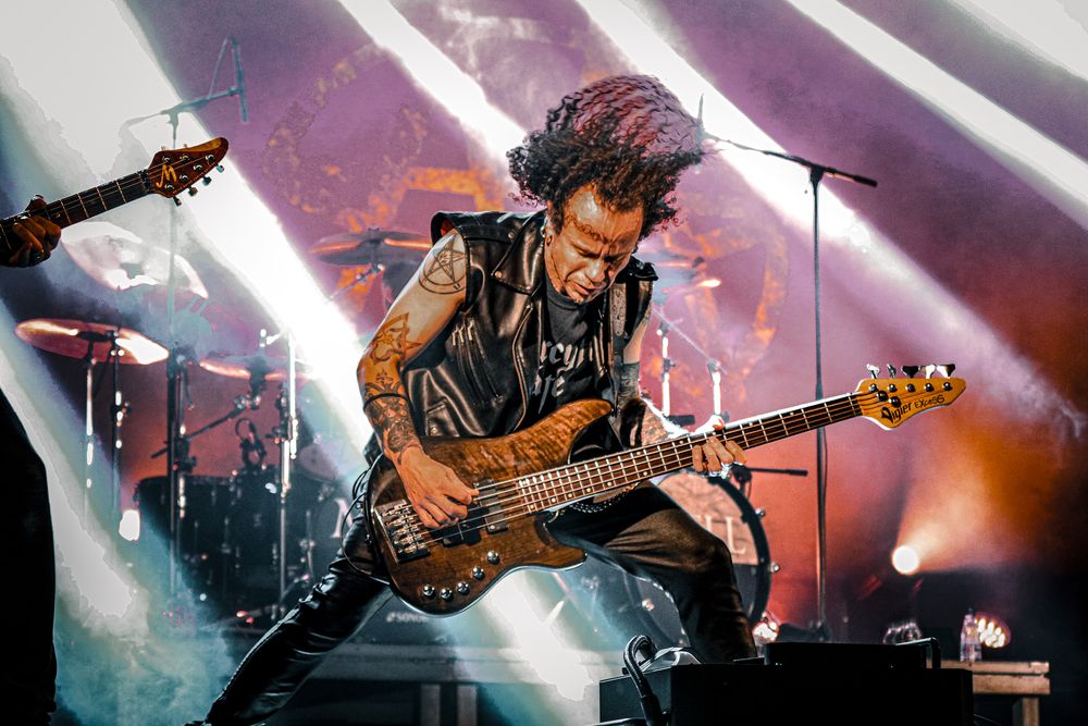 Musicians play guitars with dramatic purple and white stage lighting effects.