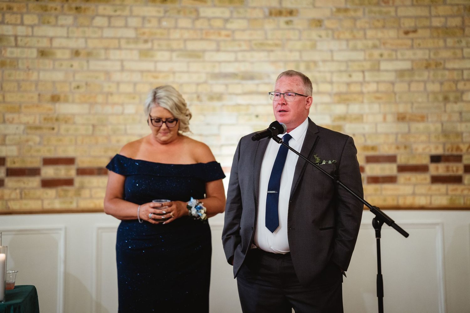 Wedding guests share emotional moments during a reception at a venue with exposed brick walls.