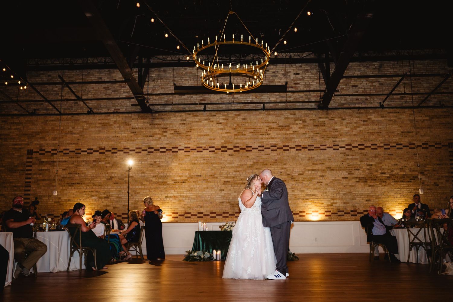 Exposed brick reception venue with string lights creating a warm ambiance for dancing.