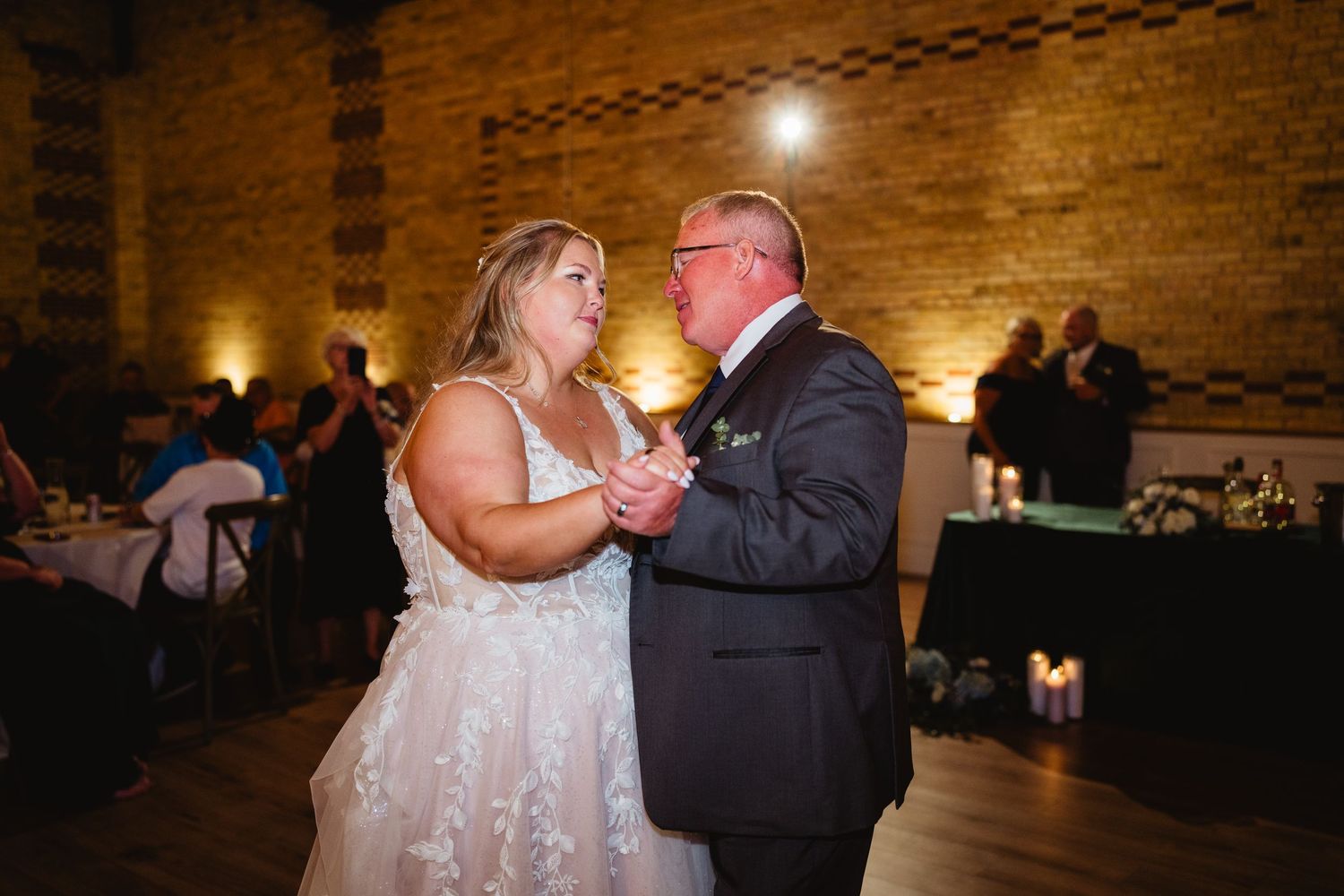 Couples dancing together during an intimate moment at a dimly lit wedding reception.