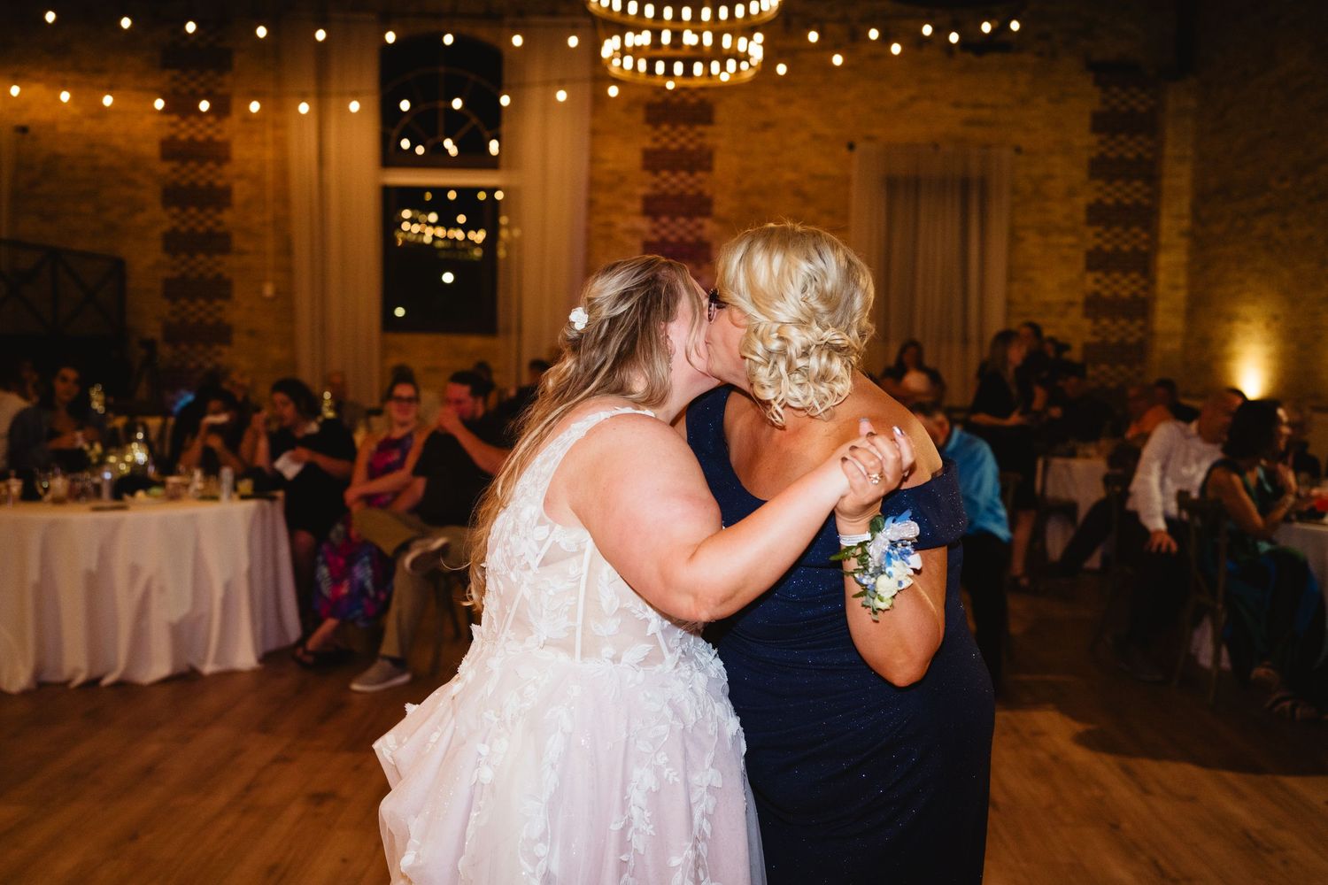 Wedding reception dance floor with string lights and couples dancing in an elegant ballroom setting.