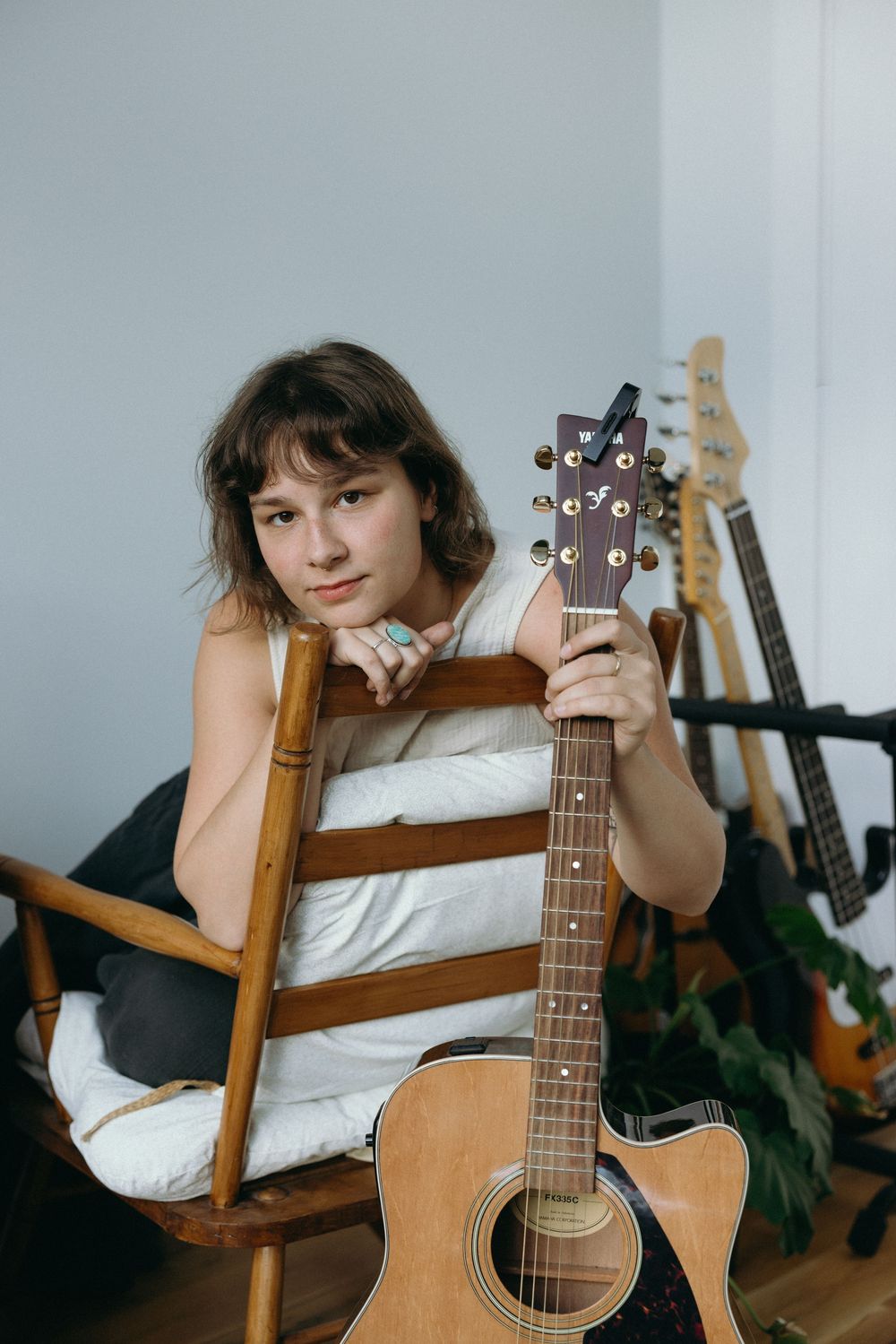 A series of photos showing an acoustic guitar being played while lounging on a wooden chair.