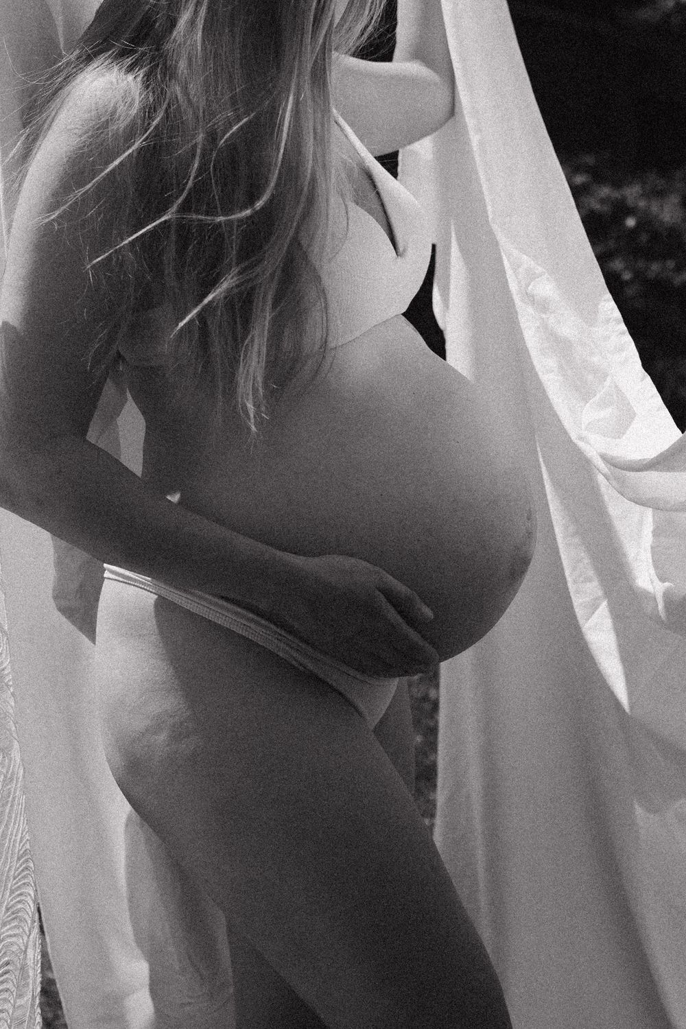 Black and white artistic maternity silhouette photos against white curtains.