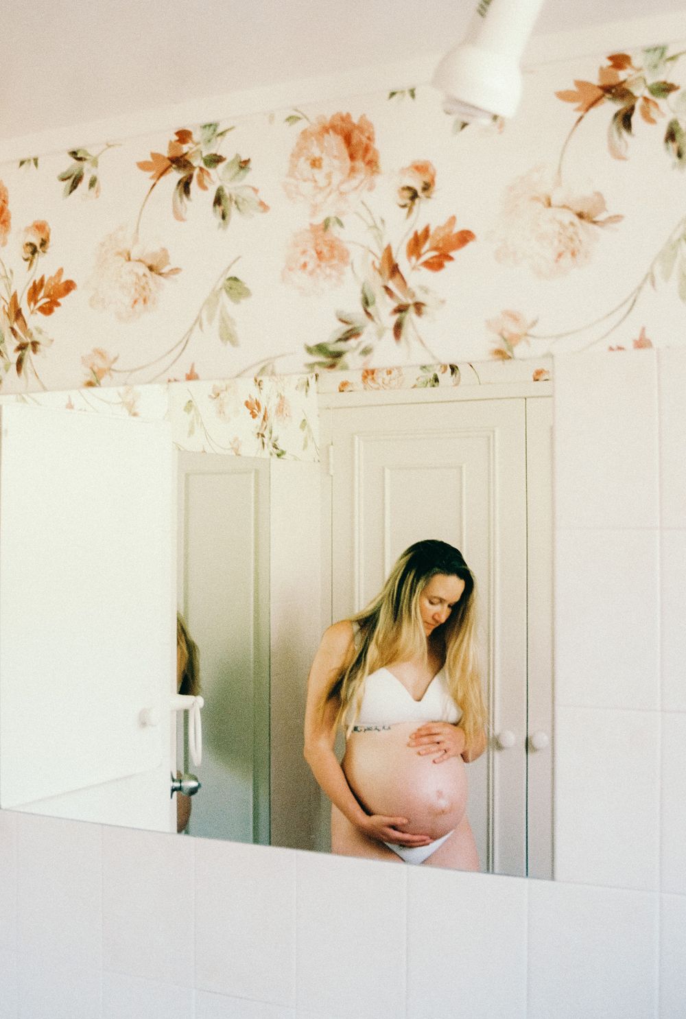 A triptych of soft, ethereal photos showing a person in pink against white walls with delicate floral wallpaper above.