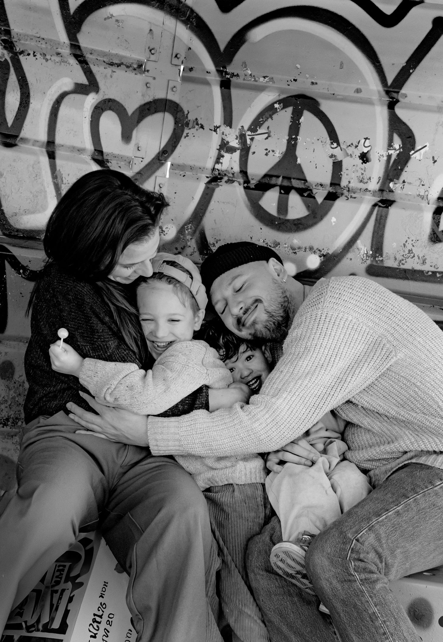 Black and white photos showing intimate family moments against graffiti wall.