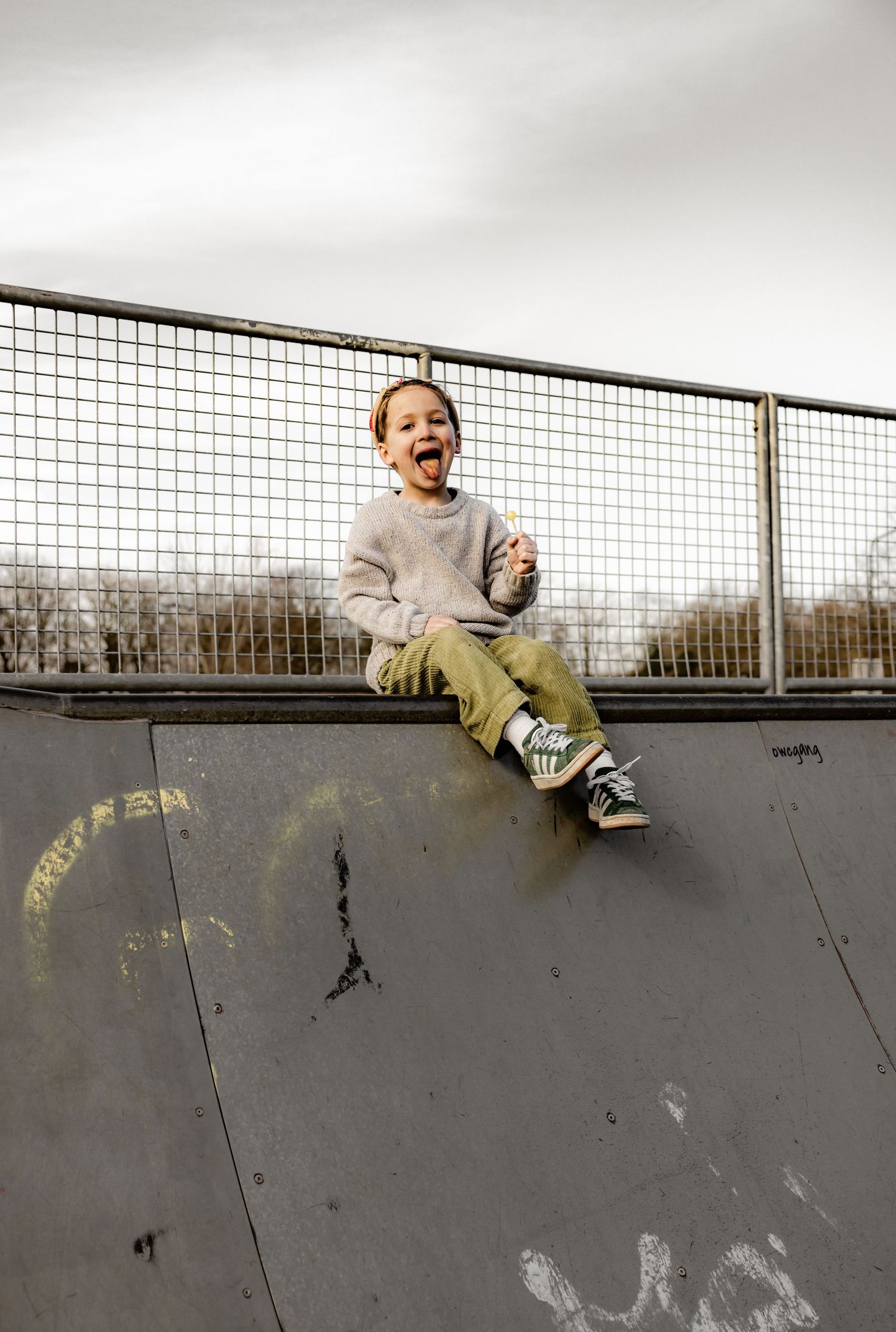 Playful sequence of someone sliding down a concrete skate ramp while wearing casual attire.