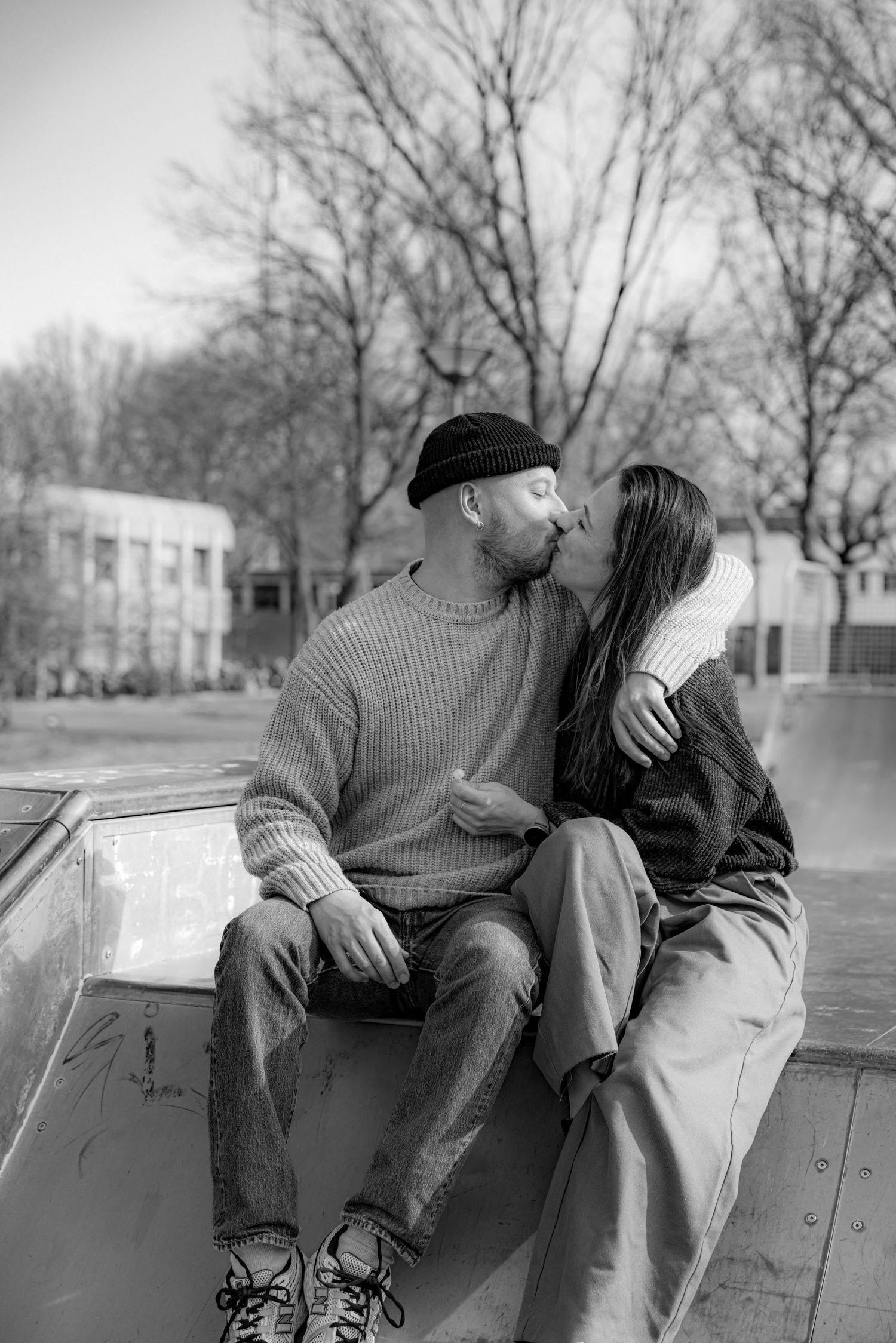 Black and white series showing two people sitting together on a concrete ledge at a skate park.