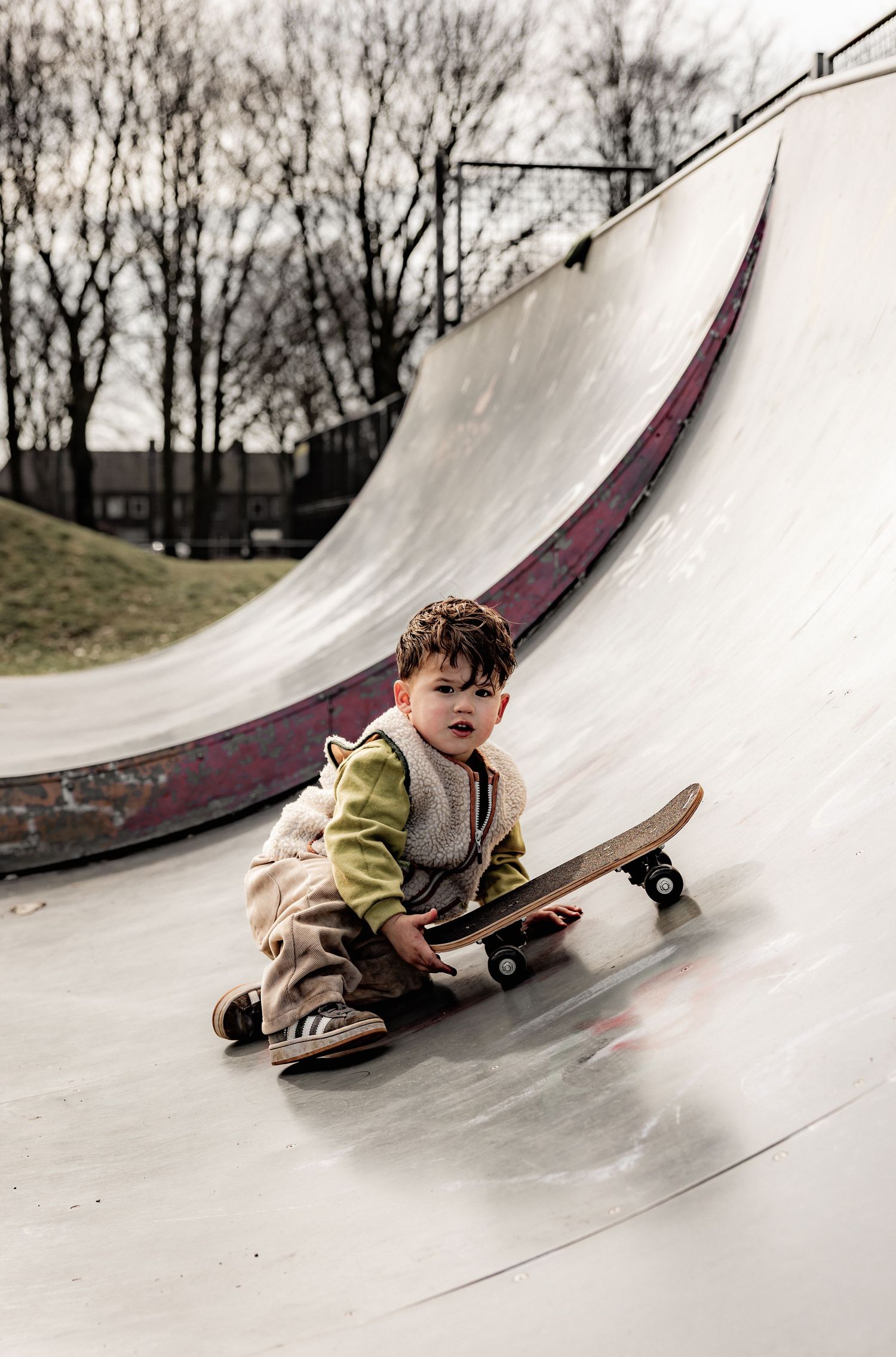 Sequence showing a child sliding down a curved skate ramp surface in casual clothing.