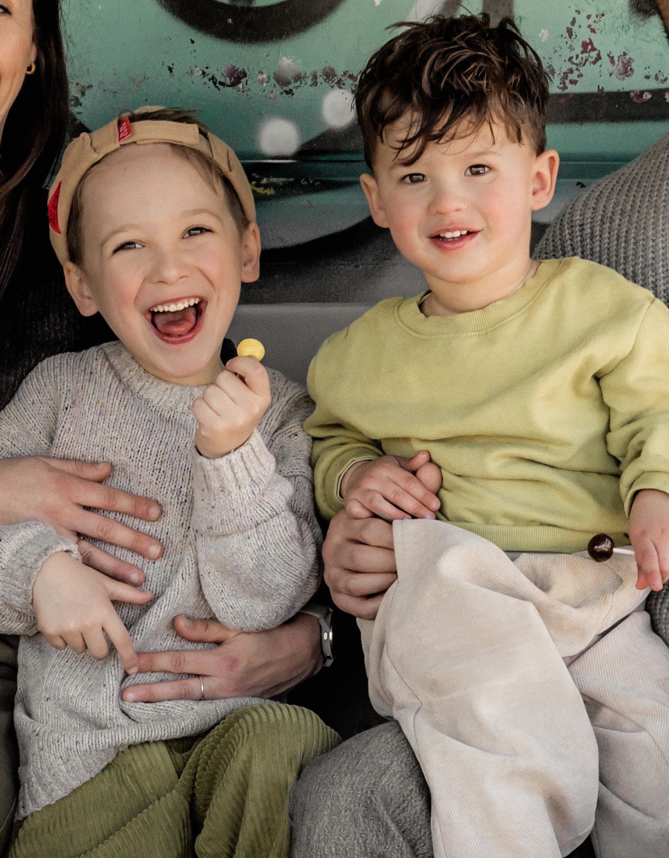 Children sitting together laughing and sharing snacks in casual clothing.
