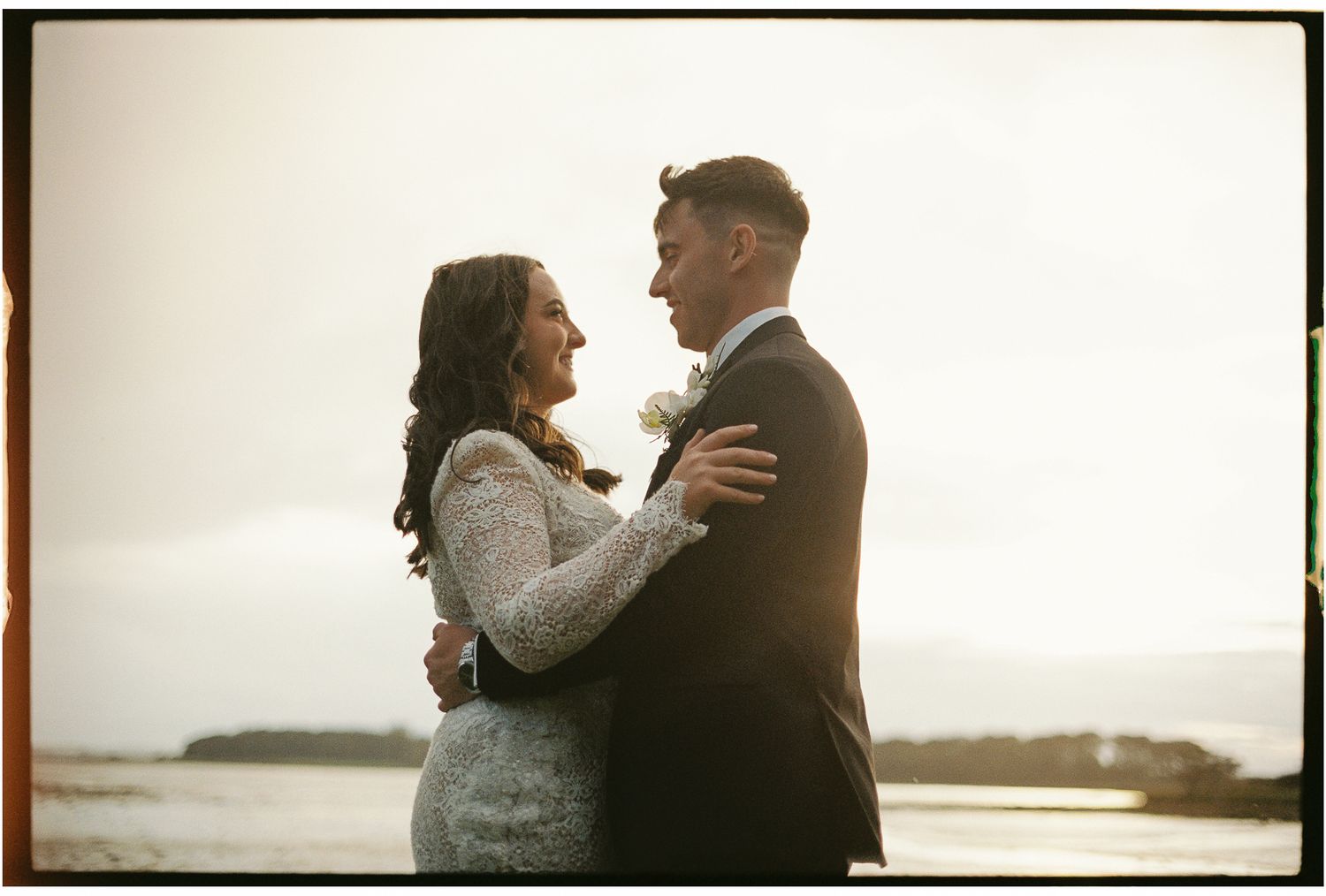 Romantic silhouette of couple embracing during golden hour sunset.