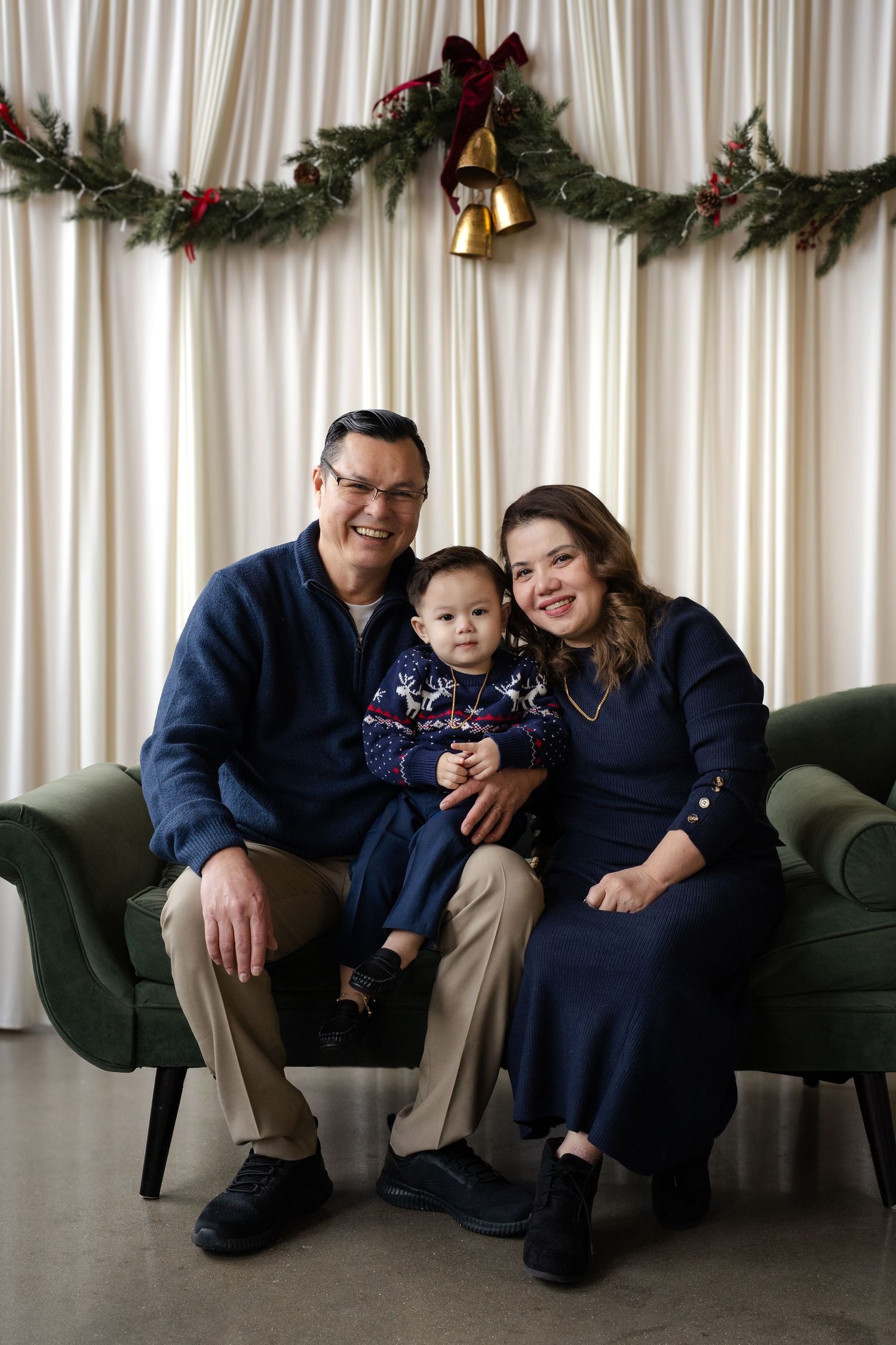 Family holiday portrait on green couch with festive garland decorations.