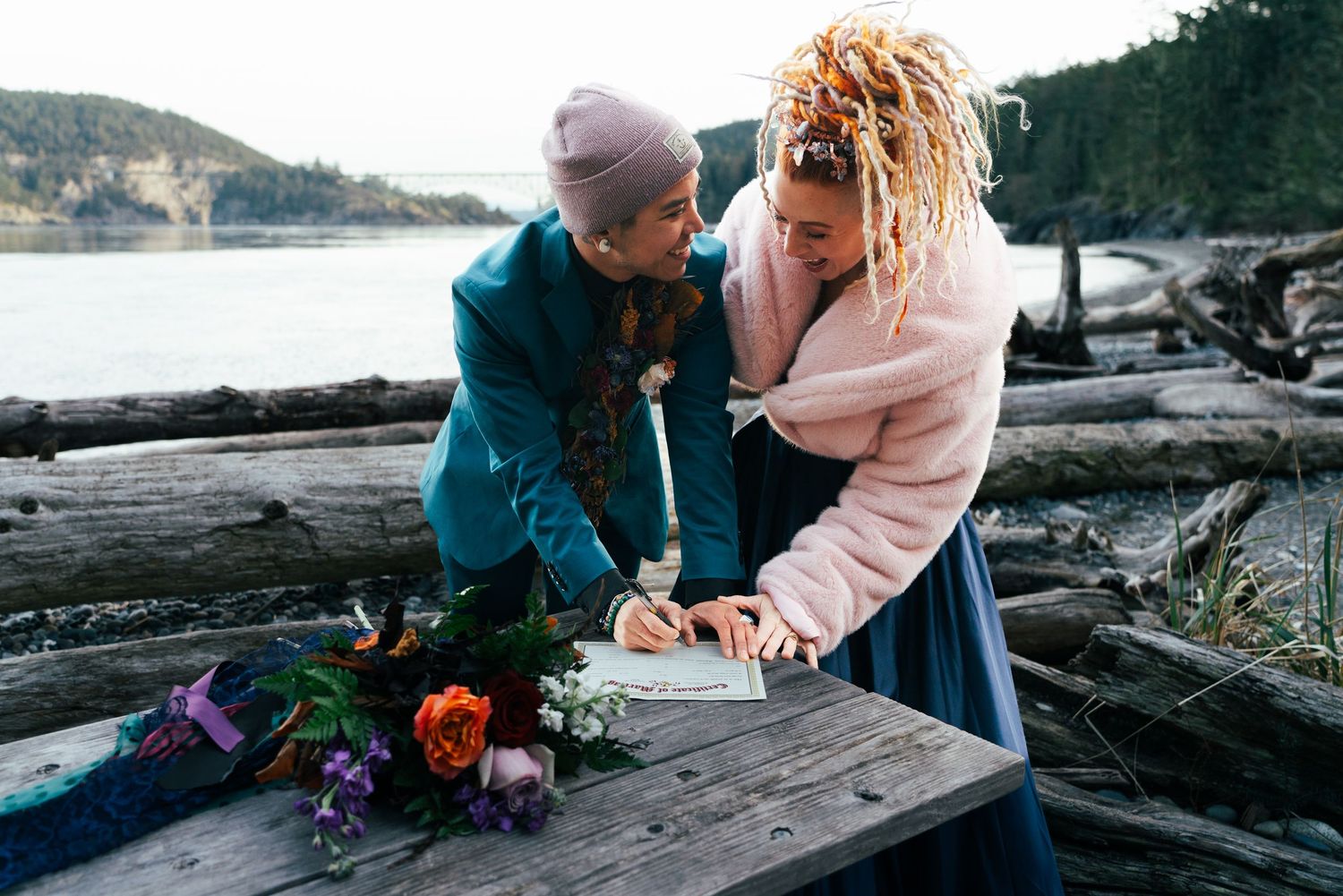 A couple signing their marriage certificate at an elopement at Deception Pass State Park, WA. Captured by Savvy Photography.