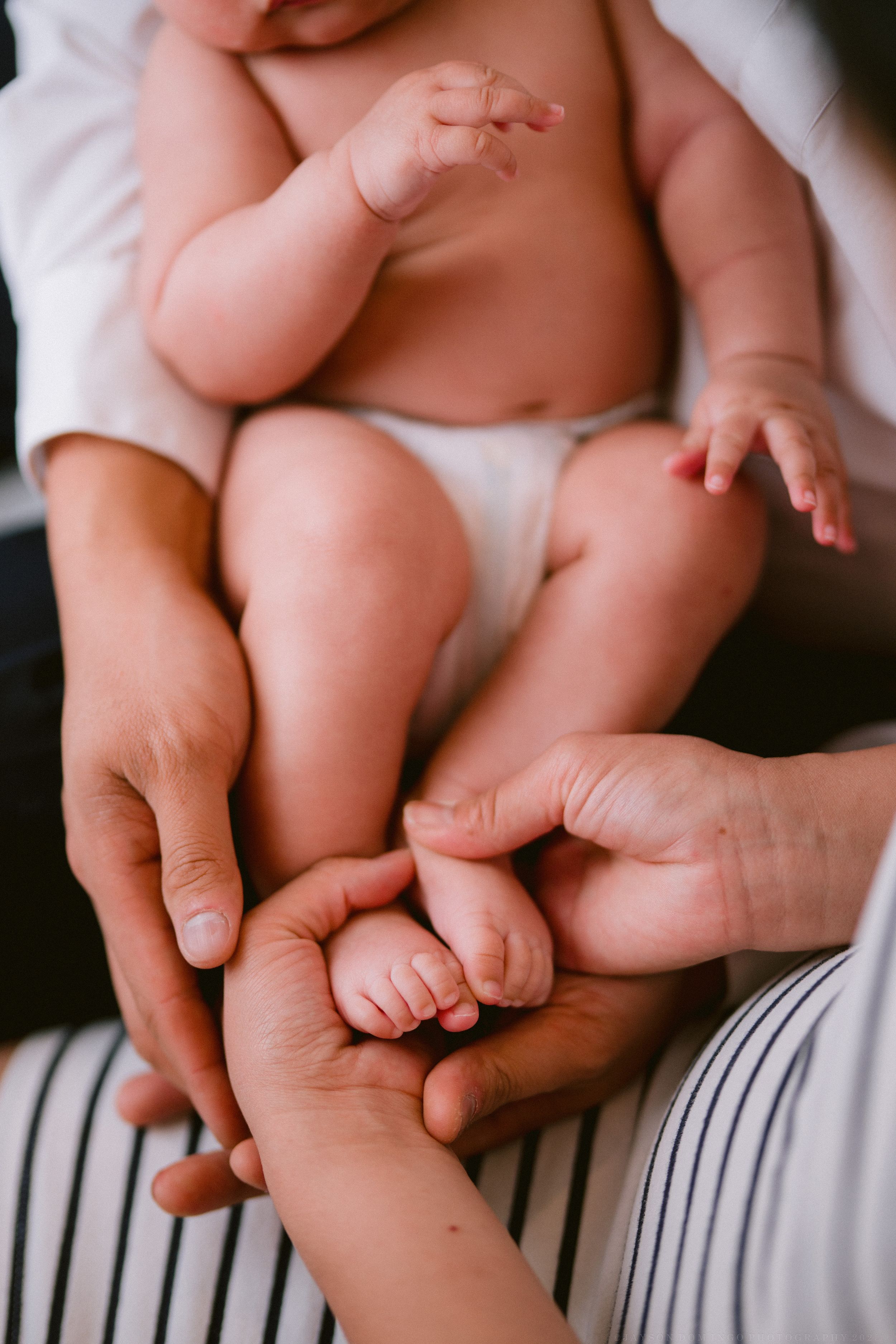 Close-up of tiny baby feet and toes resting on striped fabric.