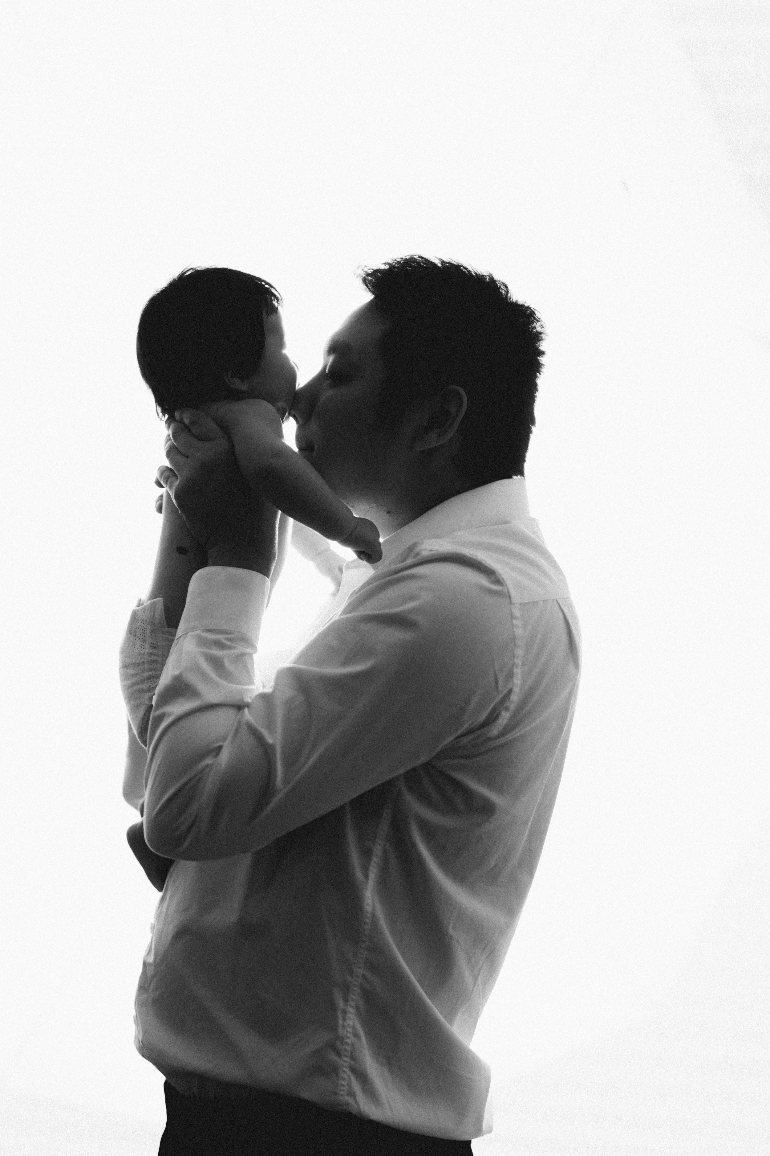 Silhouette profile of person holding infant against white background.