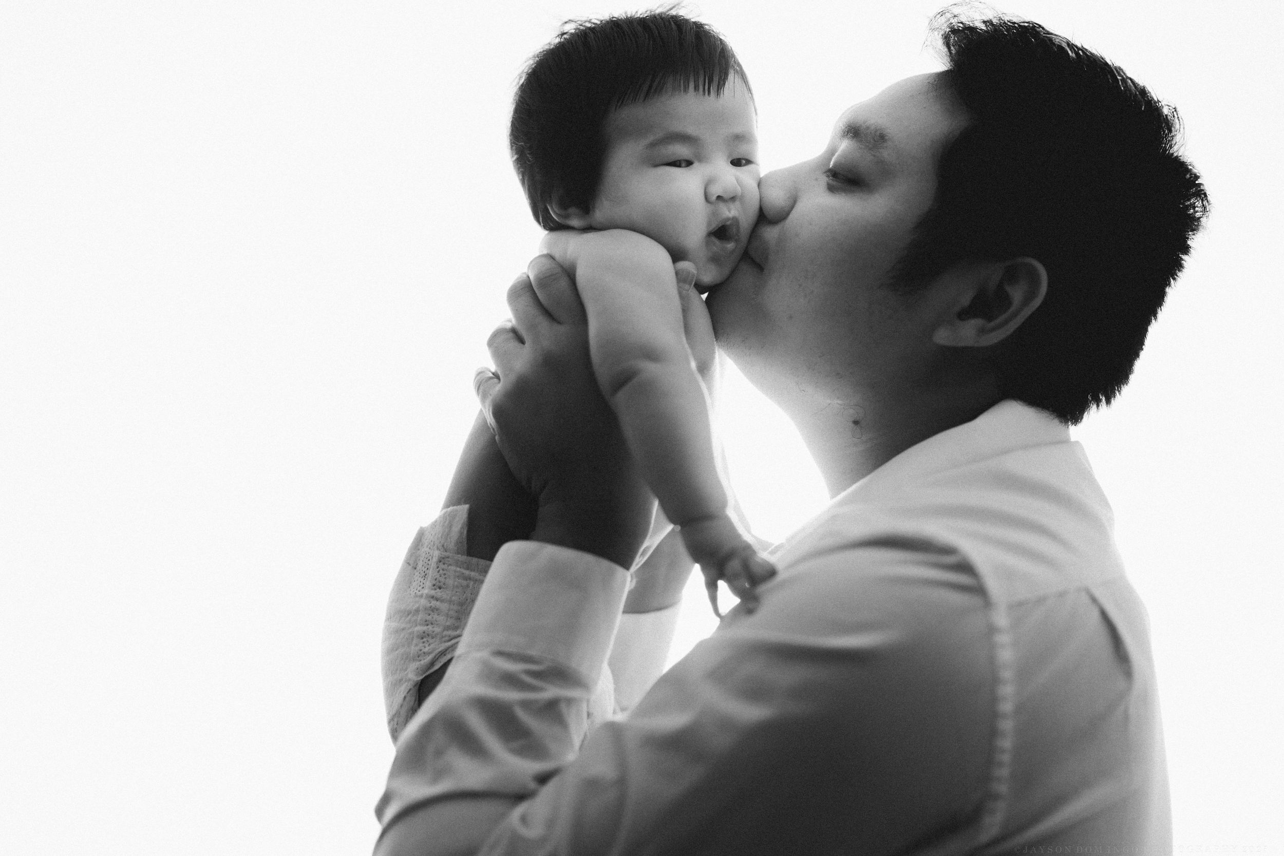 A heartwarming black and white portrait capturing an intimate parental moment of affection.